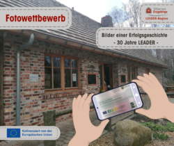 Das Foto zeigt ein historisches Haus, dass von einem Smartphone fotografiert wird mit dem Logo von LEADER